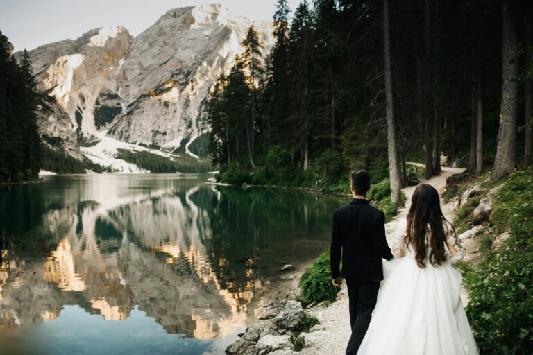 Newlyweds walking by the scenic Lake Braies in Italy with stunning mountain views.