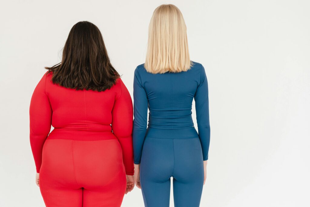 Two women of different body types in colorful activewear, showcasing diversity and fitness.
