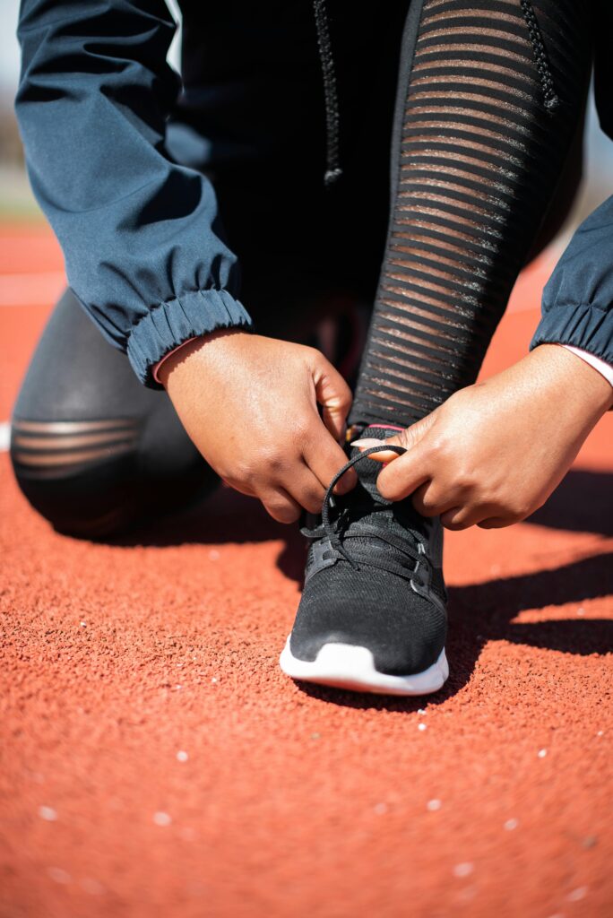 Hands tying shoelaces on running track, preparing for workout.