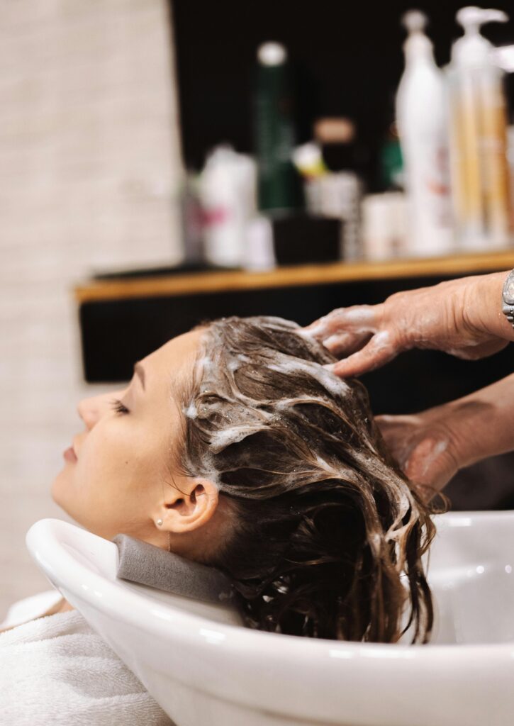 A woman enjoys a relaxing hair wash at a salon sink, showcasing a calm pampering moment.